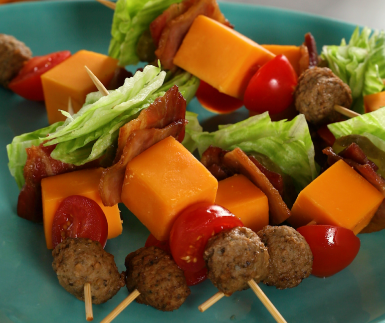 Meat, cheese, and lettuce skewers stacked on a green plate