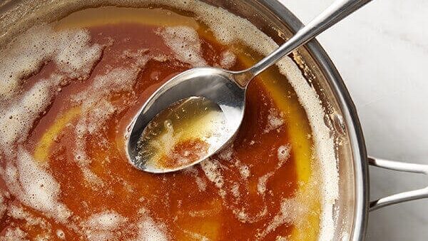 Overhead shot of a pan filled with brown butter with a spoon inside