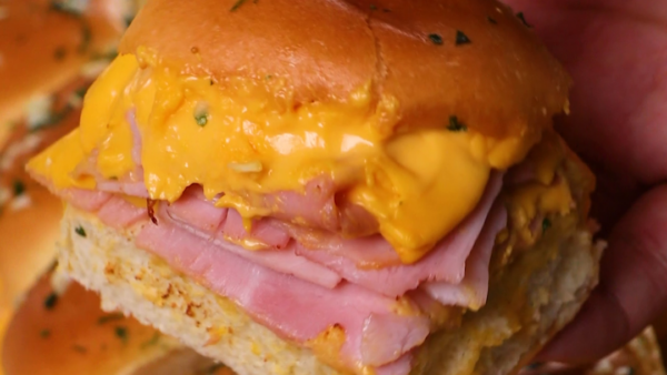 hand holding a ham and cheese slider