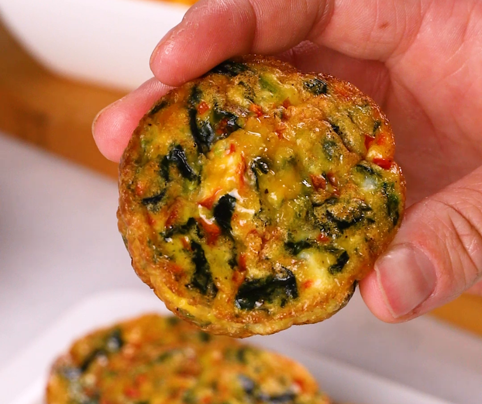 a hand holding a loaded egg bite