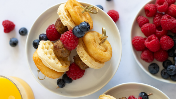 Two plates with breakfast skewers on them